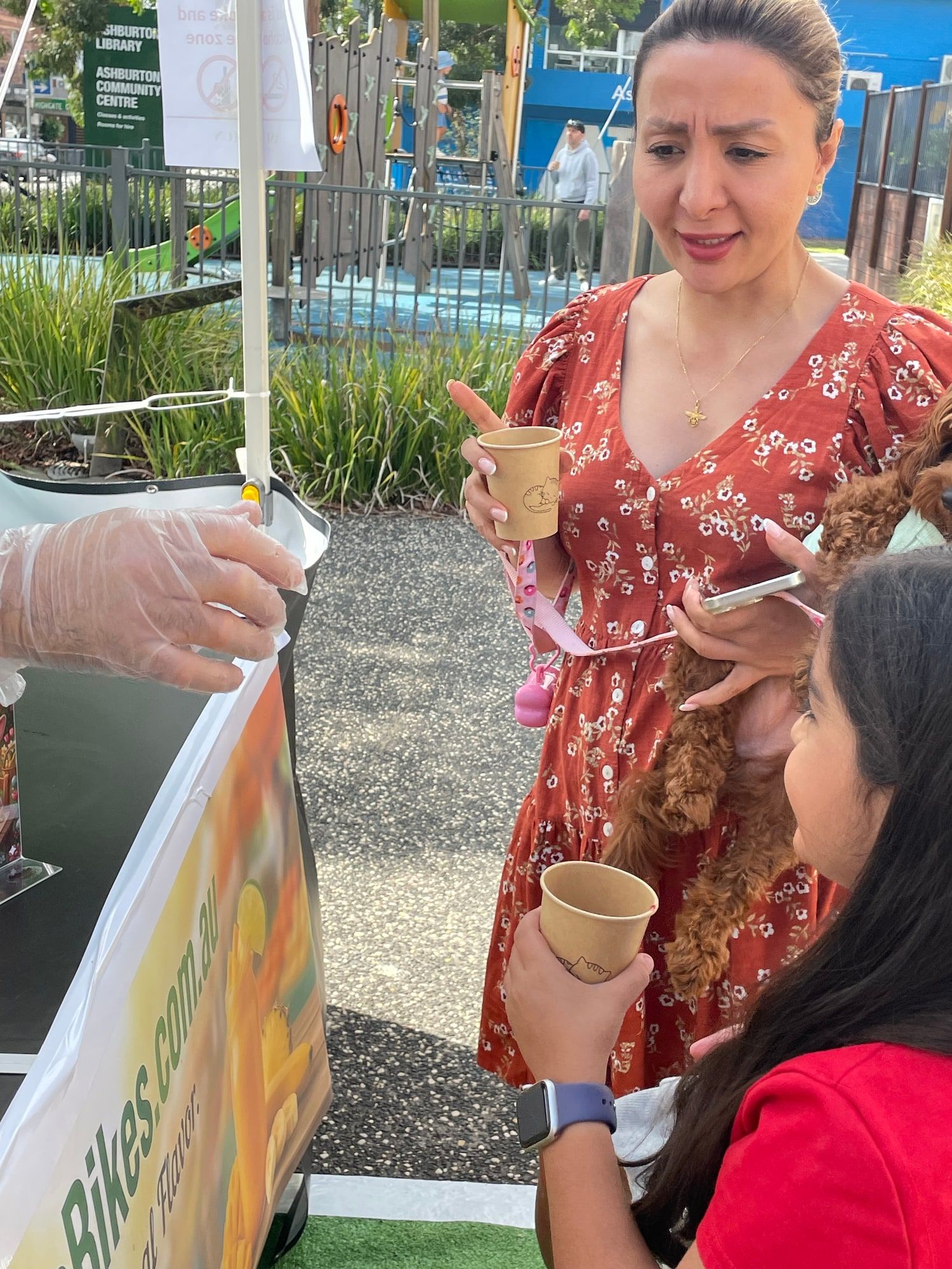 Staff hand freshly blended smoothies in paper cups to guests